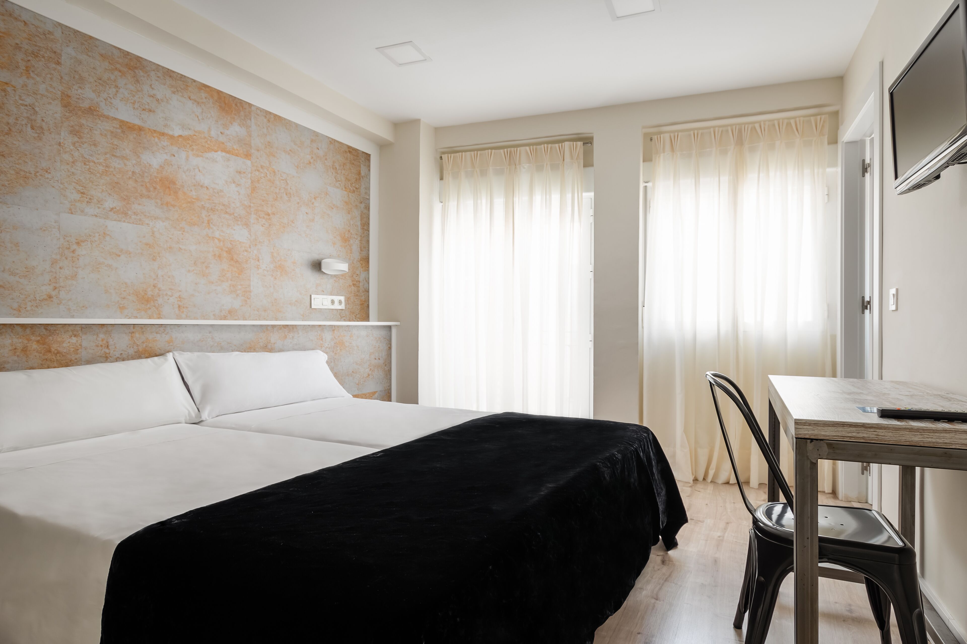 A hotel room with a large bed, a desk, and a chair.