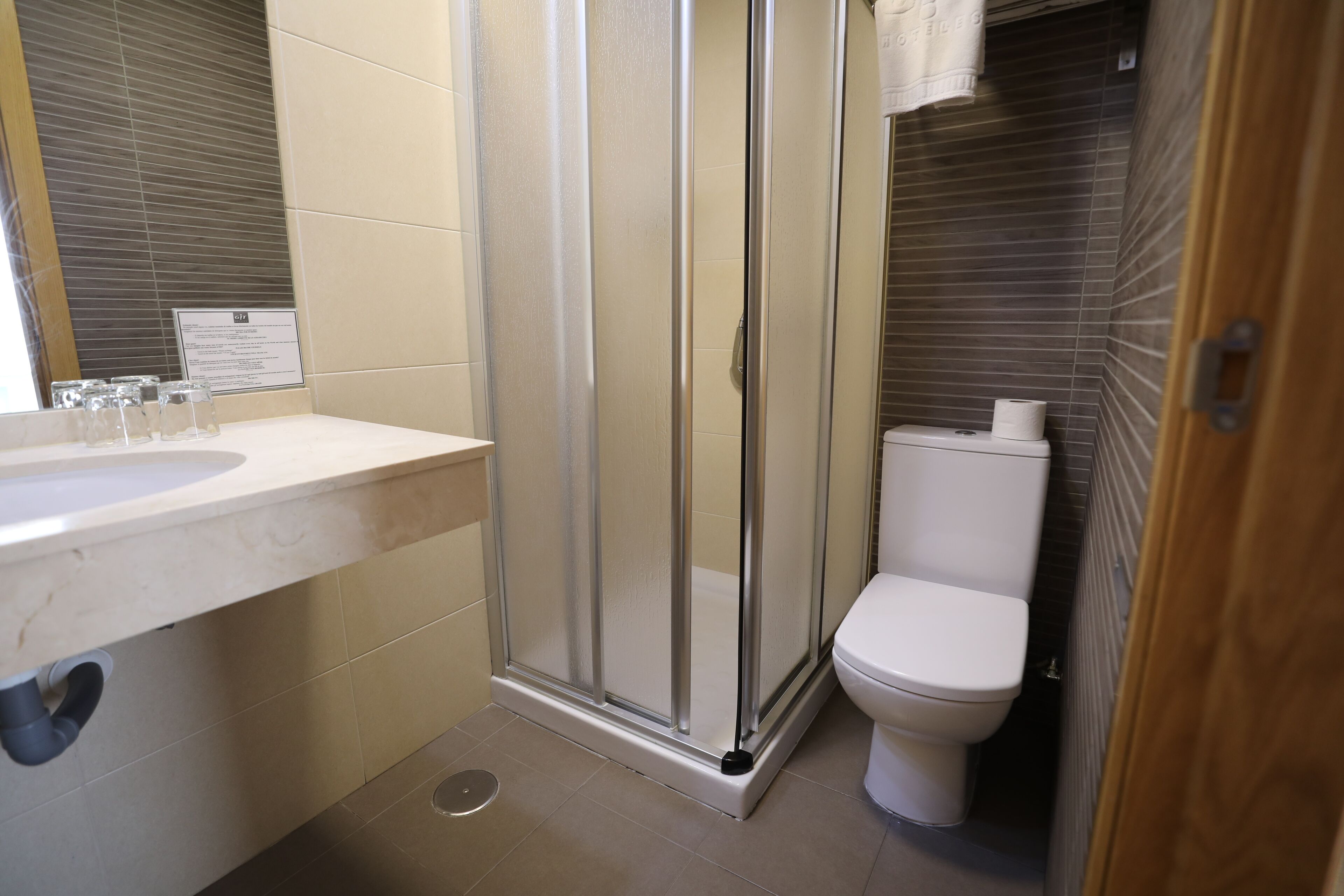 A bathroom with a glass shower enclosure, a toilet, and a sink with a mirror.