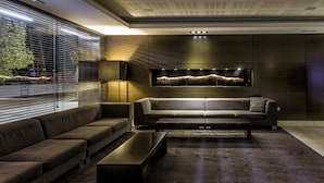 A modern living room with a dark brown sectional sofa, a coffee table, and a large window with blinds.