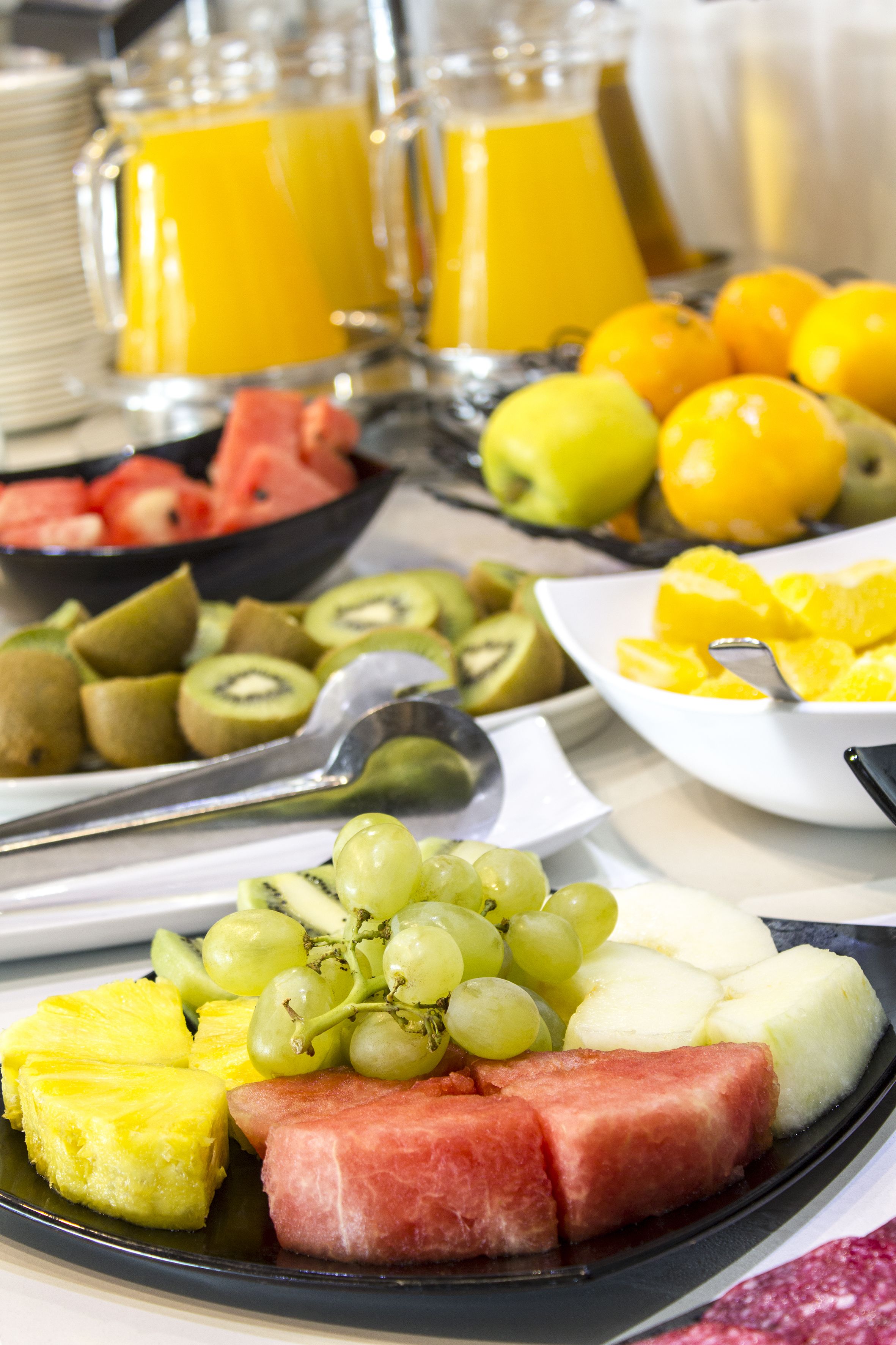 Een ontbijtbuffet met diverse soorten fruit en drankjes.