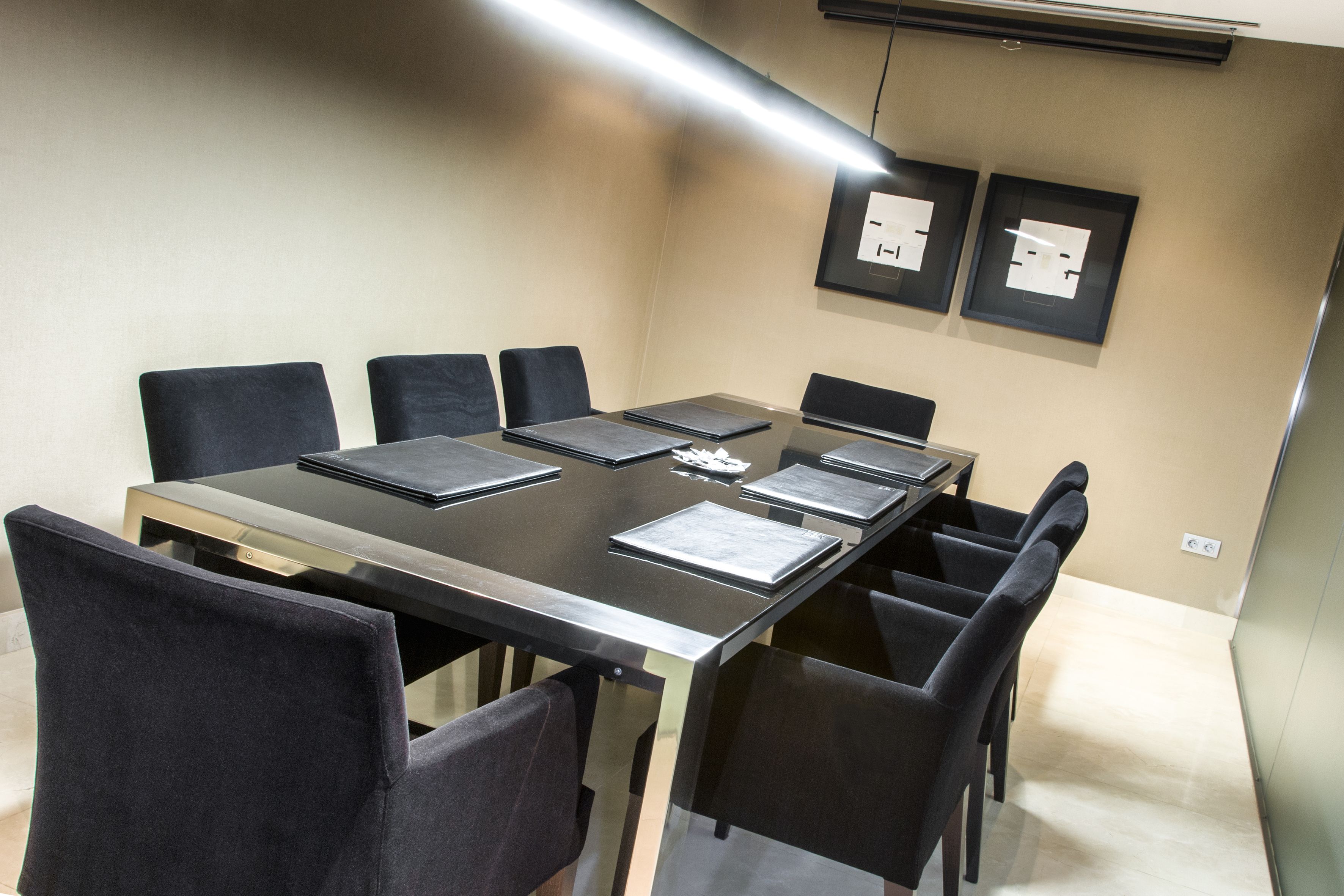 A conference room with a long table, black chairs, and framed certificates on the wall.