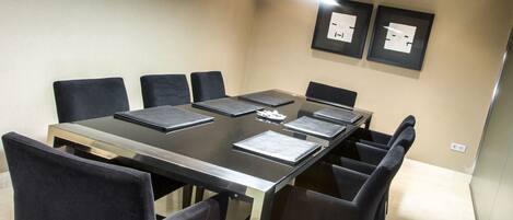 A conference room with a long table, black chairs, and framed certificates on the wall.