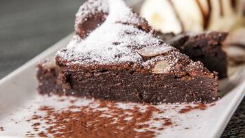 Un plato de postre con una porción de pastel de chocolate y una bola de helado.