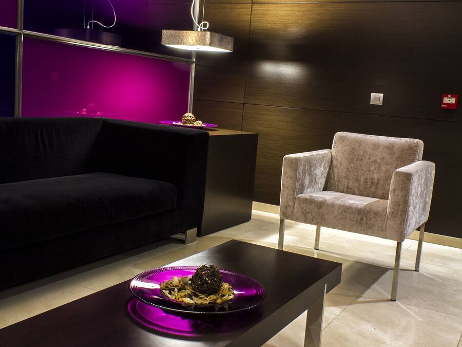 Un interior moderno con un sofá oscuro, un sillón de color claro y una mesa de centro minimalista con objetos decorativos.