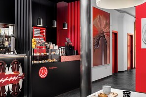 A modern coffee shop with a black counter, red accents, and a menu board. - Hotel del Pintor Historical Center, by Hoteles con Cultura (Málaga)