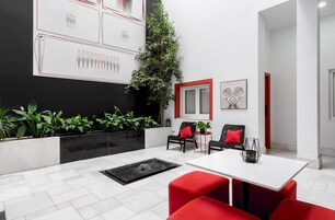 A modern interior with a white tiled floor, red and black furniture, a large plant, and artwork on the walls.