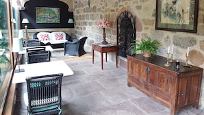 A cozy room with stone walls, a fireplace, wicker furniture, and a wooden cabinet.