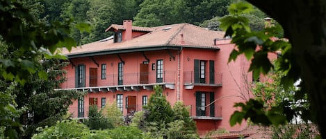 A multi-story building with balconies, surrounded by lush greenery.
