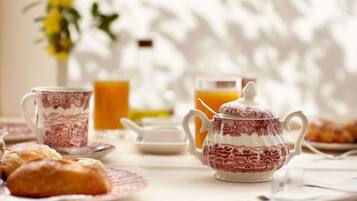 A breakfast setting with a teapot, cups, and pastries on a table.