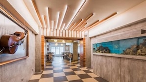 A hotel corridor with a checkered floor, wooden paneling, and a large aquarium on the right.
