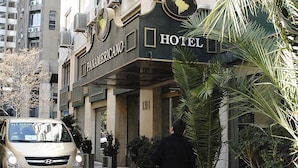 A hotel entrance with a sign reading "PANAMERICANO HOTEL," a palm tree, and a parked car.