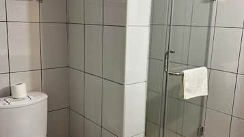 Un baño con inodoro, cabina de ducha y un perchero para toallas.