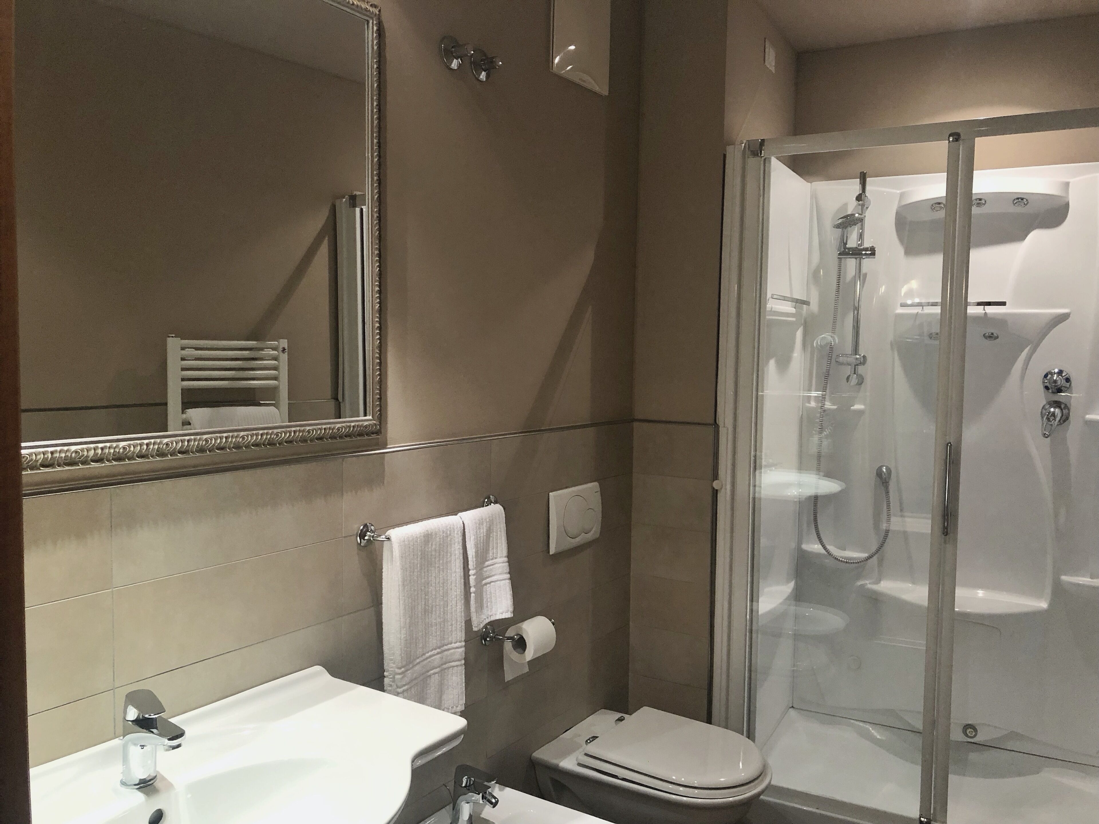 Ein modernes Badezimmer mit einer Glaskabine zur Dusche, einem weißen Waschbecken und einer Toilette.
