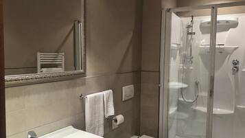 Ein modernes Badezimmer mit einer Glaskabine zur Dusche, einem weißen Waschbecken und einer Toilette.