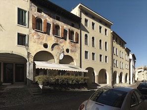 A building with multiple windows, a covered entrance, and a cobblestone street. - Hotel Canon D'Oro (Conegliano)