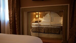 A hotel room with a large bed, a mirrored wardrobe, and a nightstand with a lamp. - Hotel Canon D'Oro (Conegliano)