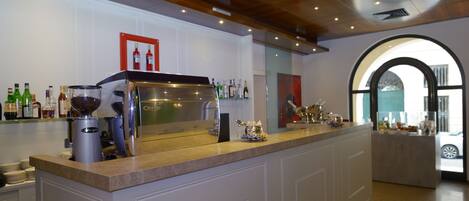 A bar area with a polished counter, a coffee machine, and various bottles.