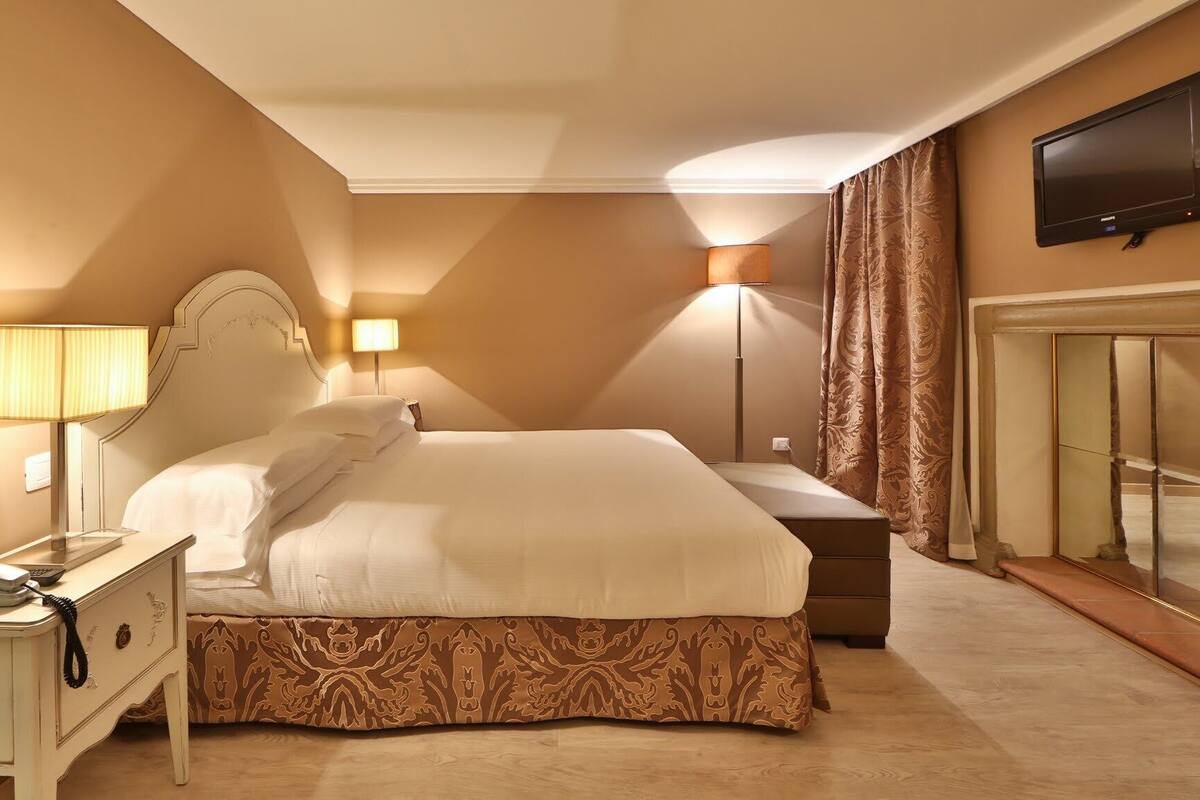 Une chambre d’hôtel avec un grand lit, des lampes de chevet, un téléphone sur la table de chevet, un téléviseur à écran plat fixé au mur et un miroir.