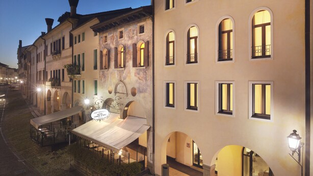 A hotel with multiple balconies, a covered outdoor seating area, and a well-lit facade. - Hotel Canon D'Oro (Conegliano)