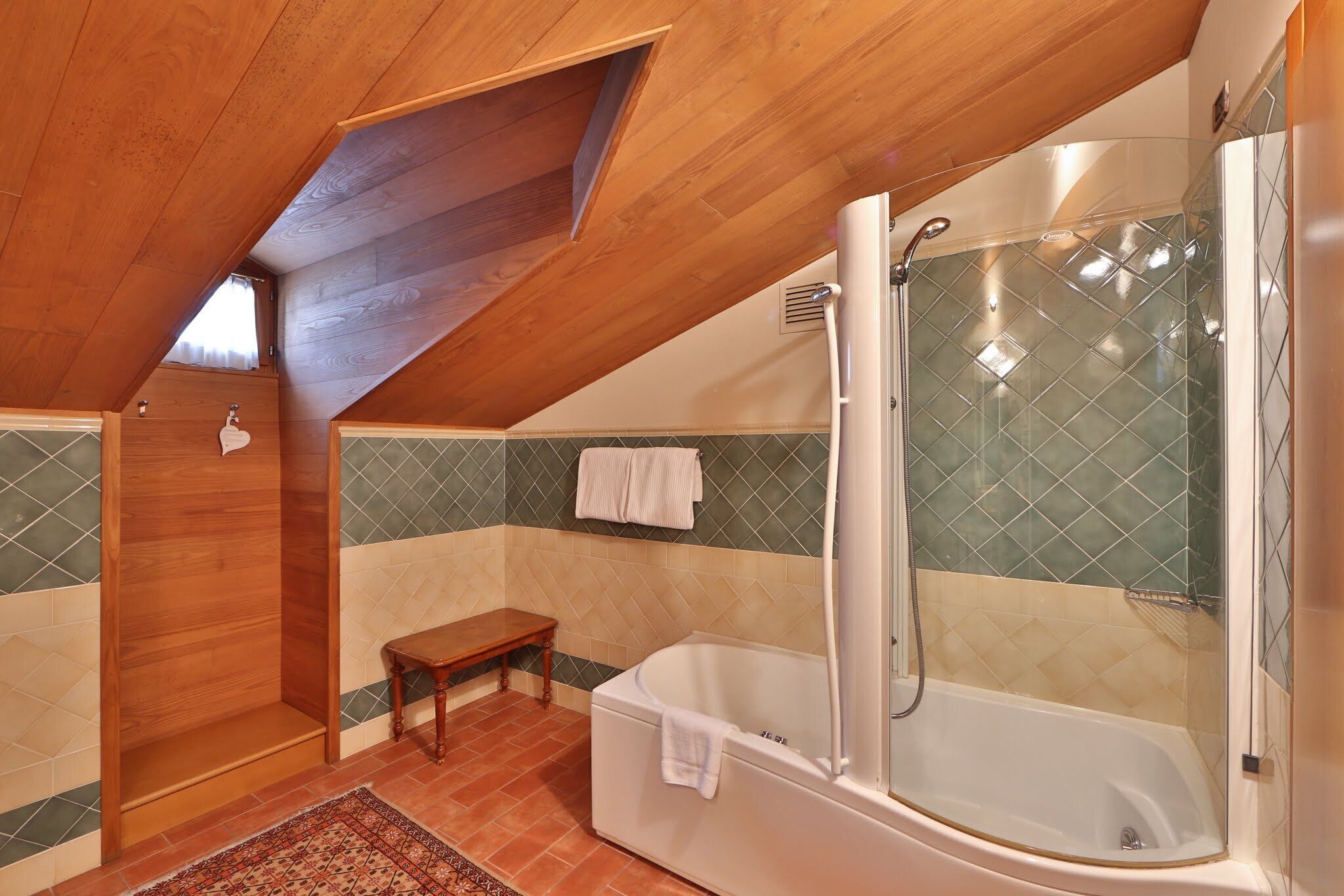 A bathroom with a wooden ceiling, a bathtub, a shower, and a bench.