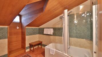 A bathroom with a wooden ceiling, a bathtub, a shower, and a bench.