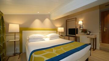 Une chambre d’hôtel avec un grand lit, des lampes de chevet, un bureau avec une chaise, une télévision et un miroir.