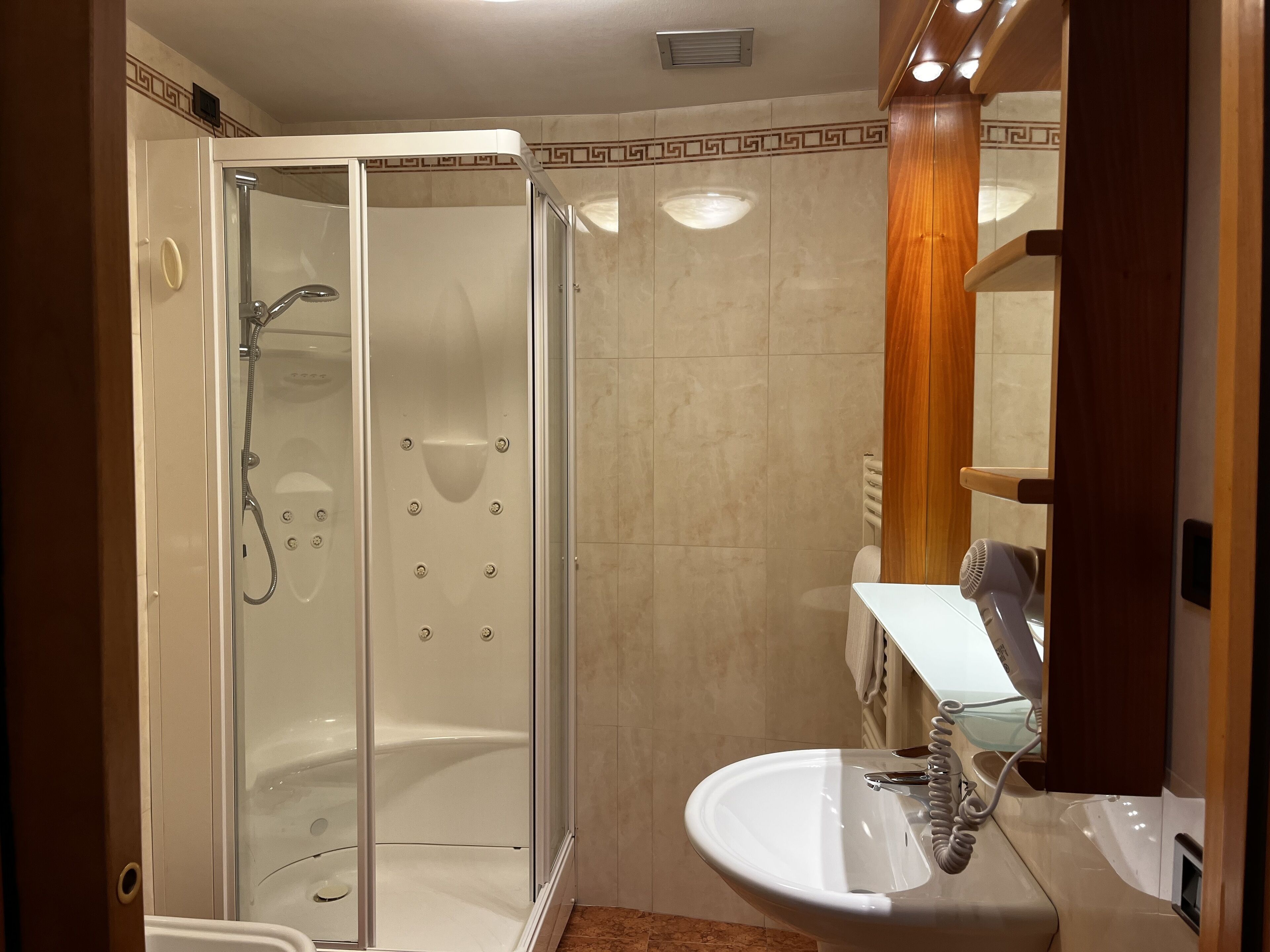 A modern bathroom with a glass-enclosed shower, a white sink, and a towel rack.