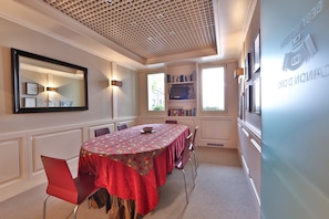 A conference room with a round table, red chairs, a bookshelf, and a large mirror. - Hotel Canon D'Oro (Conegliano)