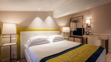 Una habitación de hotel con cama, lámparas de noche, escritorio y espejo.