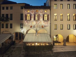 A courtyard with a dining table and chairs, surrounded by buildings with arched windows and a mural.