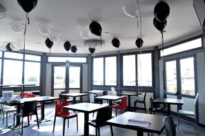 A classroom with tables and chairs, balloons hanging from the ceiling, and large windows. - Hotel San Giorgio (Civitavecchia)