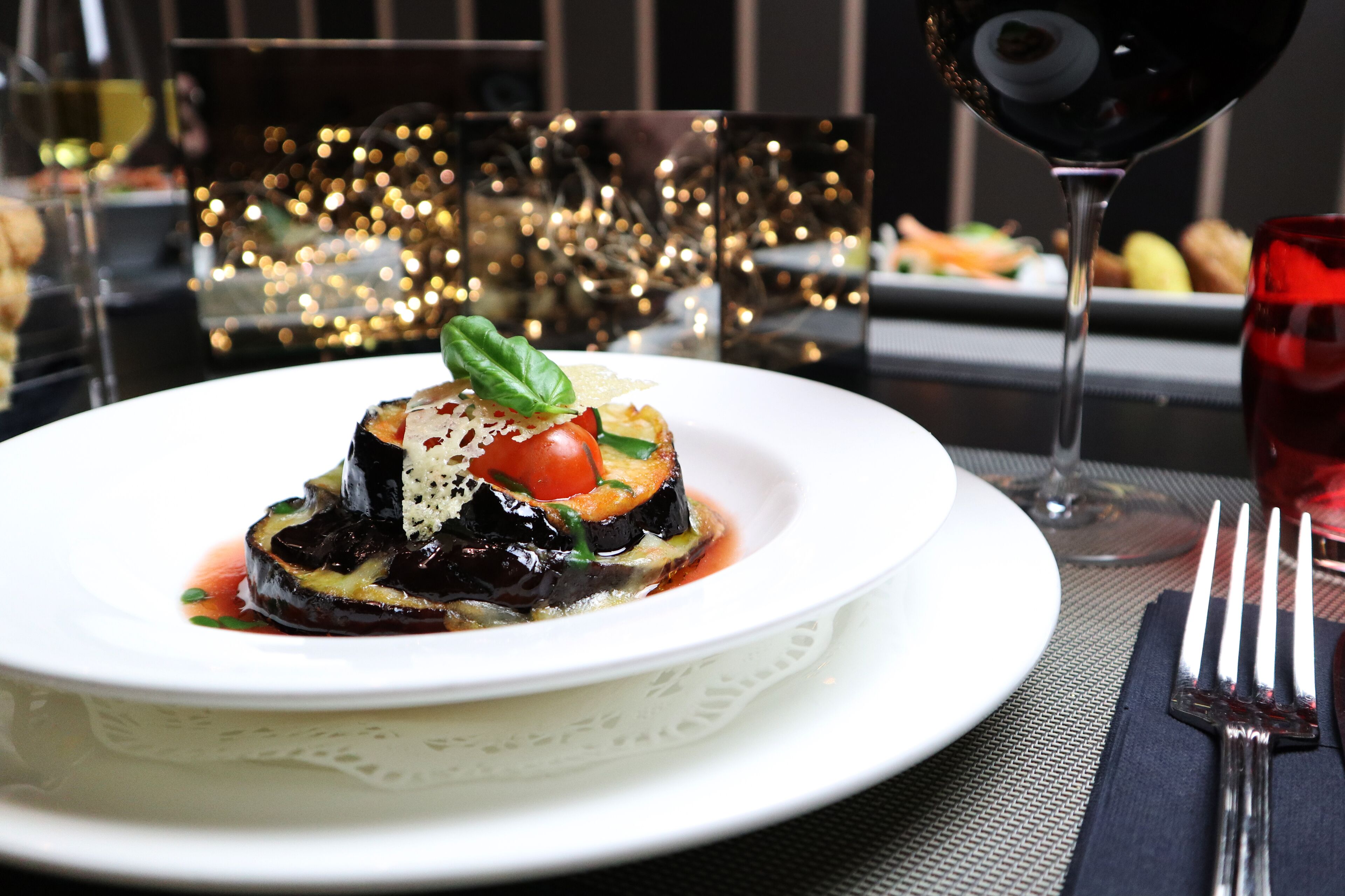 Un plato de comida con una copa de vino tinto y un tenedor sobre una mesa.