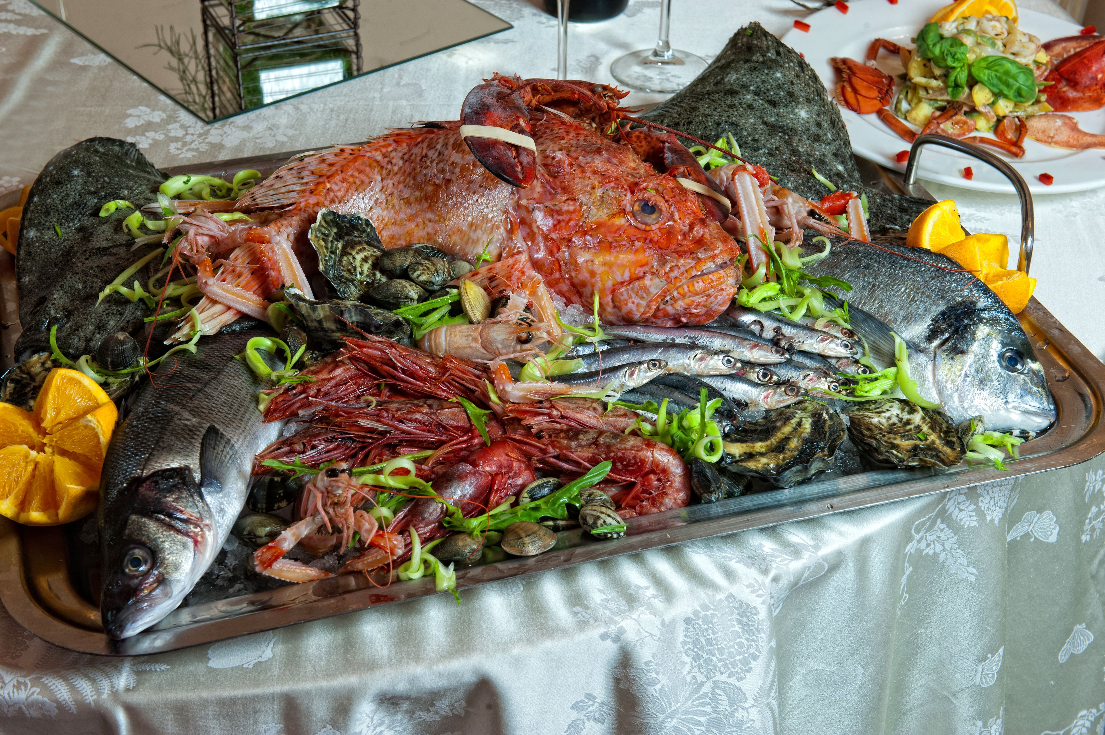 A seafood platter with various types of fish and shellfish, including a whole fish, shrimp, and mussels, arranged on a tray.