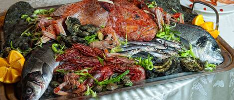 A seafood platter with various types of fish and shellfish, including a whole fish, shrimp, and mussels, arranged on a tray.