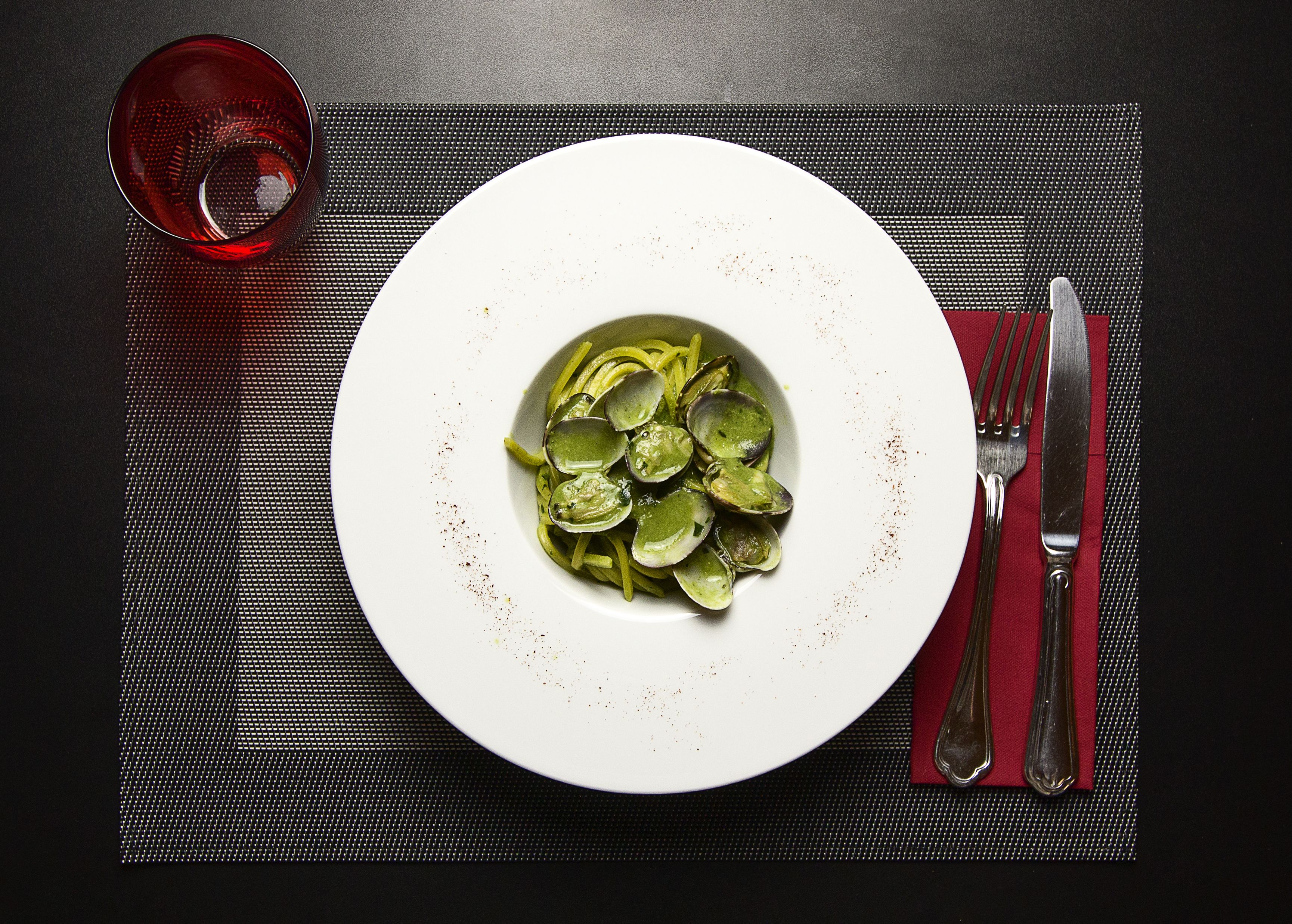 A plate of food on a black table with a red napkin and cutlery.