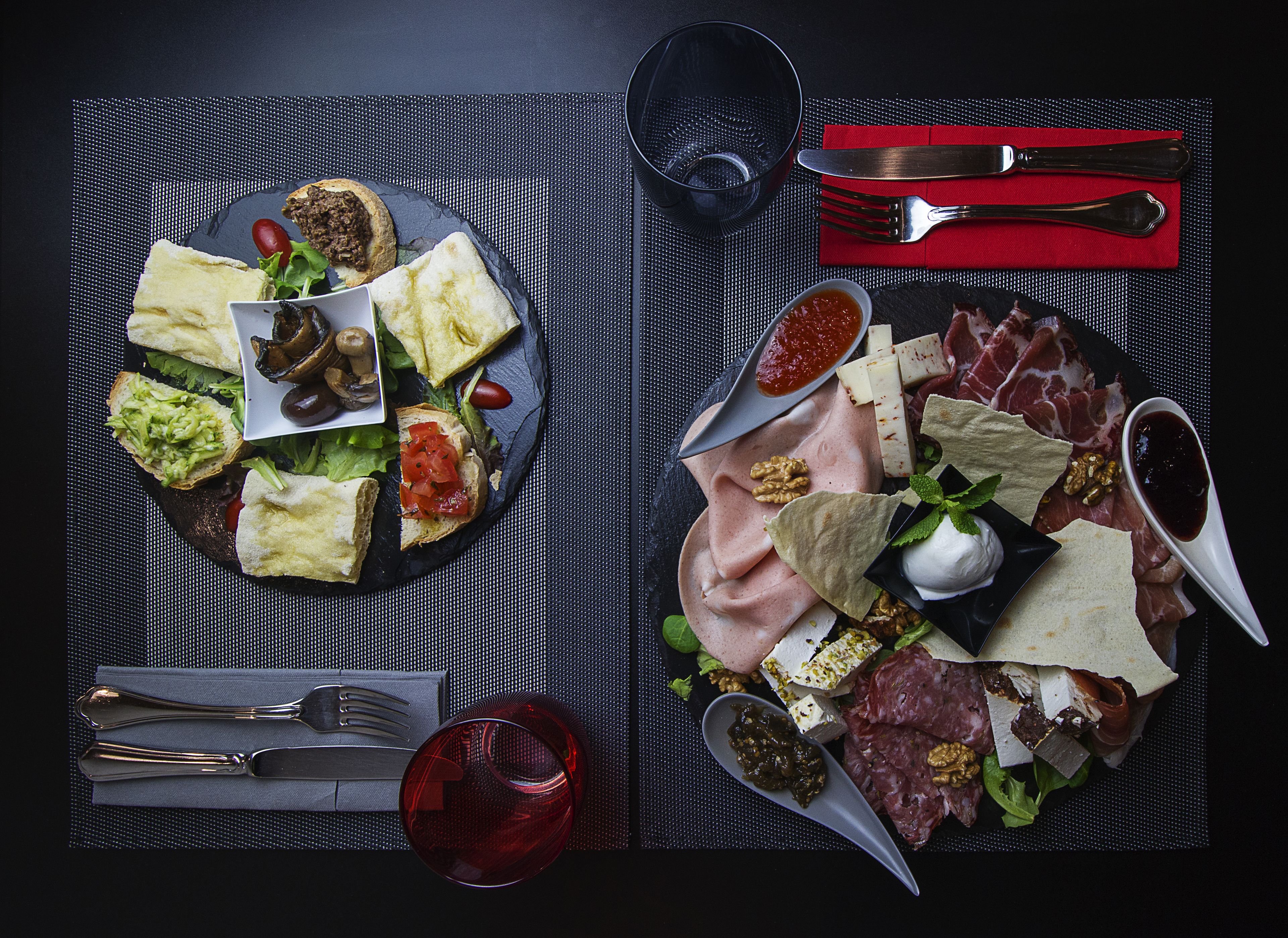 Una mesa preparada con diversos alimentos, entre ellos sándwiches, queso, carnes y salsas.