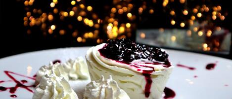 Sobremesa com chantilly e frutas vermelhas sobre um prato branco.