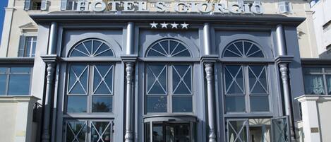 A hotel with a classic facade, large arched windows, and a prominent entrance with a revolving door.