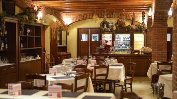 A restaurant interior with brick walls, wooden beams, and tables set for dining.