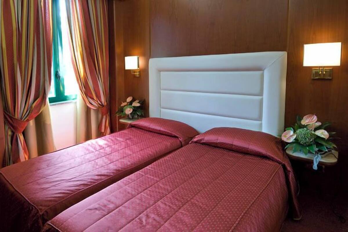 Habitación de hotel con dos camas, paredes de madera y lámparas de noche.