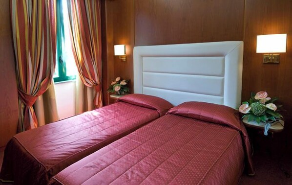 A hotel room with two beds, wooden walls, and bedside lamps.