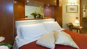 A hotel room with a large bed, a bedside table with a lamp, a mirror above the bed, and a framed picture on the wall. - AS Hotel Monza (Monza)