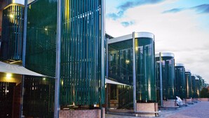 A modern building with curved glass panels and metal structures.
