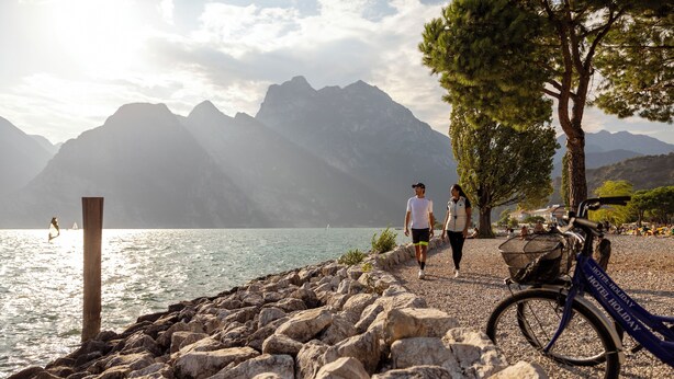 A rocky lakeside path with a bicycle and a sign indicating a hotel holiday location. - Hotel Holiday Sport & Relax (Nago-Torbole)
