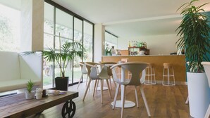 A modern dining area with a wooden table, chairs, and potted plants. - Hotel Holiday Sport & Relax (Nago-Torbole)