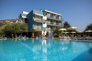 Una piscina al aire libre, sombrillas, sillones reclinables de piscina