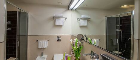 A modern bathroom with a bidet, toilet, sink, and glass shower enclosure.