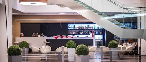 A modern lobby with a bar area, seating, and a staircase.