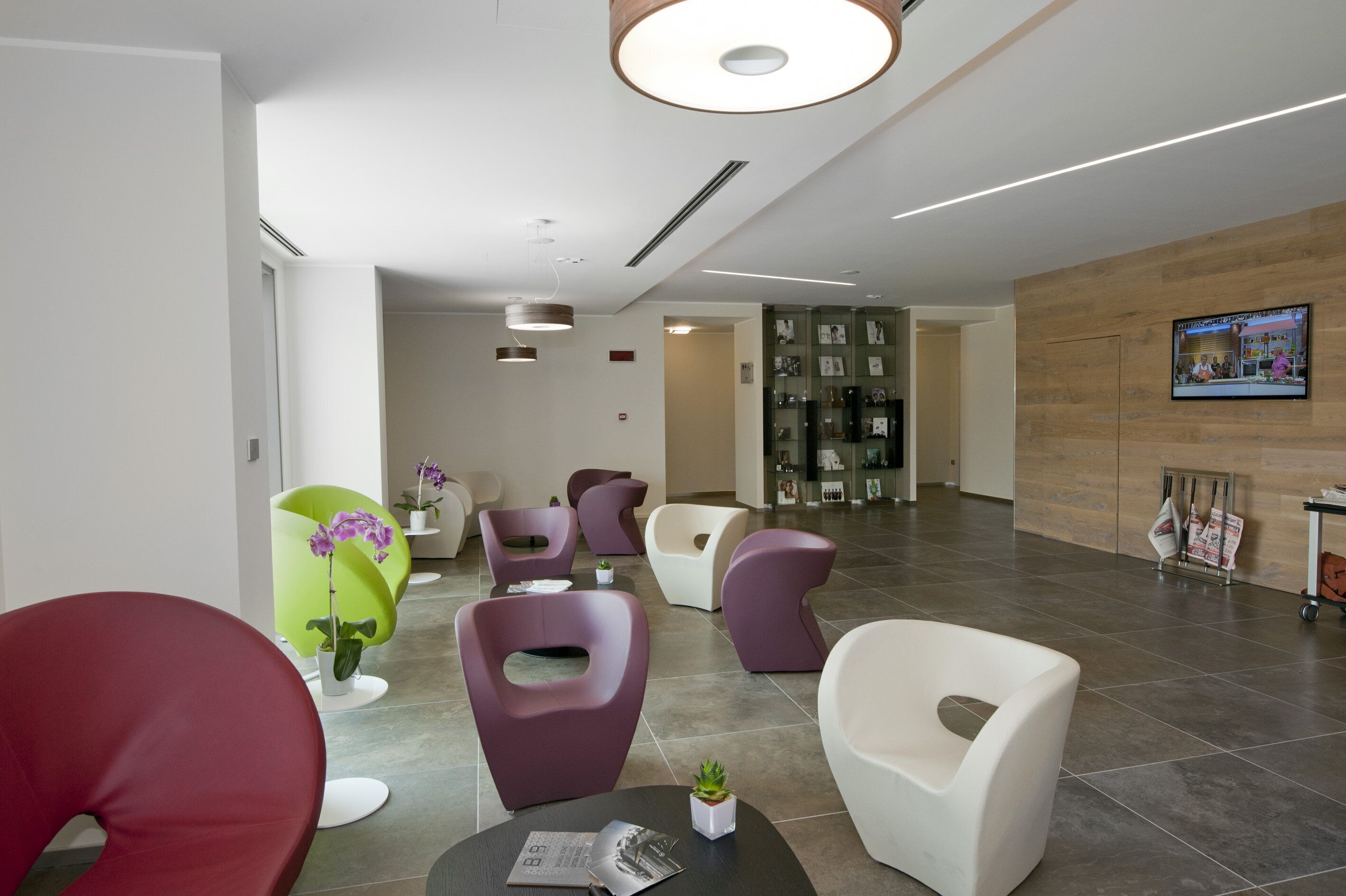 Eine moderne Lobby mit zeitgenössischer Sitzmöbeln, einem Empfangsbereich und einem Fernsehbildschirm.