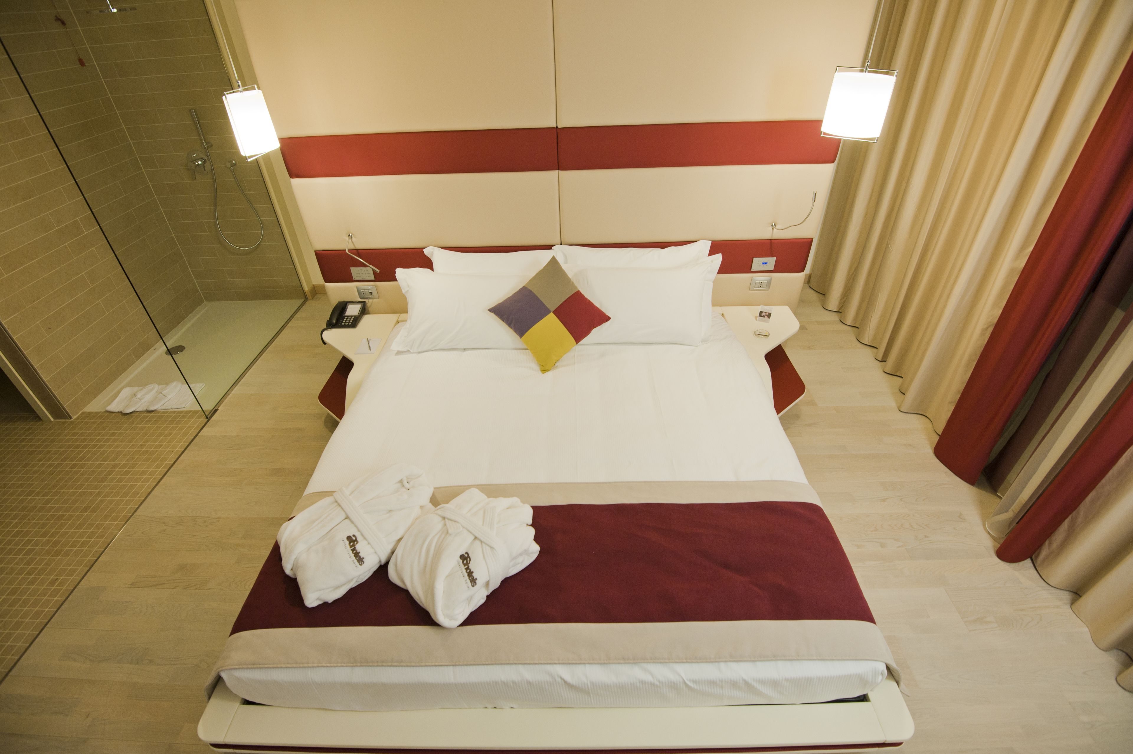 A hotel room with a large bed, a shower area, and two bedside tables with lamps.